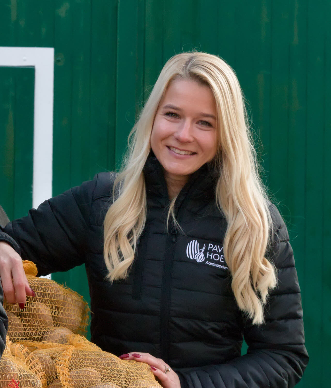 Evie van de Paviljoenhoeve in bedrijfsjas met een zak uien